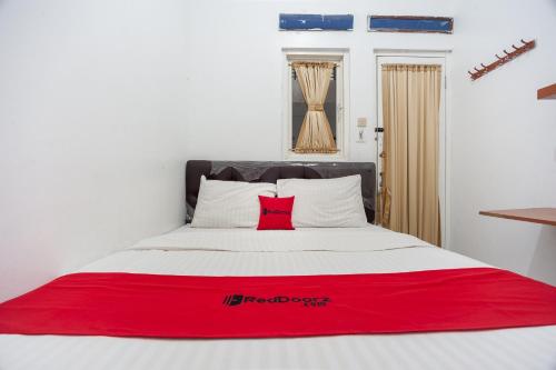 a bed with a red blanket on top of it at RedDoorz Syariah near PGC Cililitan in Jakarta