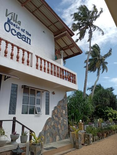 a white building with a palm tree in the background at Villa Music of the ocean in Wadduwa
