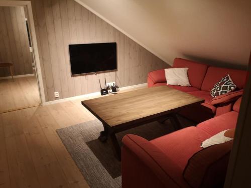 LiagardaneにあるStor og moderne hytte med panoramautsiktのリビングルーム(赤いソファ、木製テーブル付)