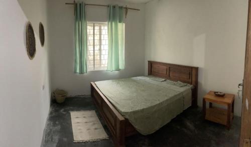 um quarto com uma cama e uma janela com cortinas verdes em Karikila em Paje