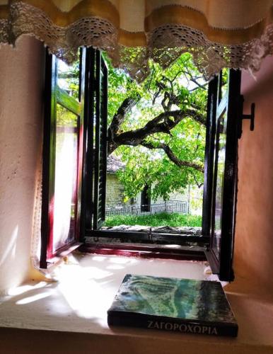 a window with a book in front of a tree at Παραδοσιακό Σπίτι στο Μονοδένδρι in Monodendri