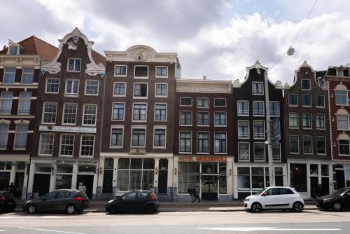 een groep gebouwen op een straat met geparkeerde auto's bij Multatuli Hotel in Amsterdam