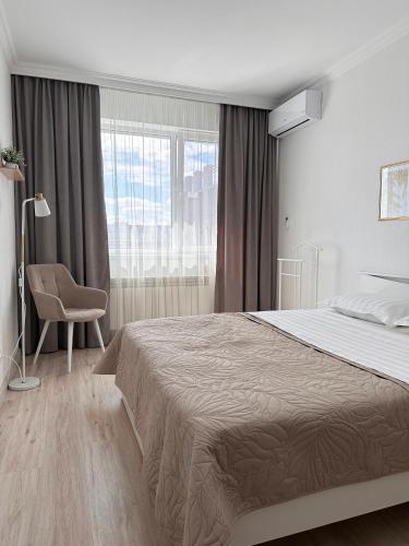 a bedroom with a bed and a chair and a window at ЖК "Light House", 1 in Astana