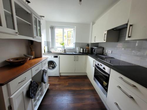 a kitchen with white cabinets and a washer and dryer at Comfortable Two Bedroom Modern Apartment in London