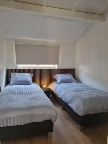 een slaapkamer met 2 bedden en een lamp op een houten vloer bij vakantiewoning 266 in De Panne