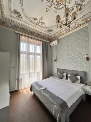 a bedroom with a large white bed with a ceiling at Nizami Central Street Hotel in Baku