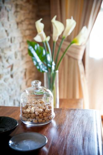 a jar of rocks on a table with a vase with white flowers at Relais Montemarino in Borgomale