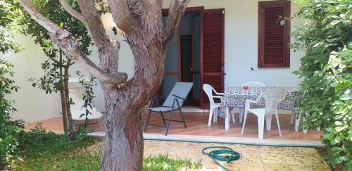 a patio with a table and chairs and a tree at Villetta Mare in SantʼAndrea