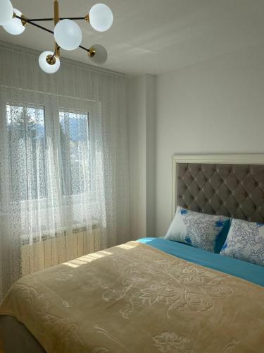 a bedroom with a bed and a window with curtains at Pirlitor Mountain Apartment in Žabljak