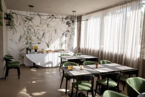 a dining room with tables and green chairs and a wall at Bellevue Hill apartment in Zadar