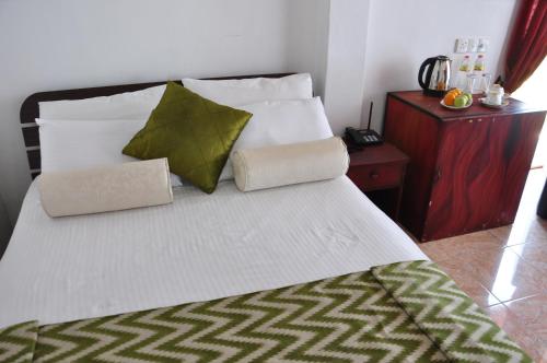 a bed with two pillows on it in a room at Villa Hotel in Trincomalee