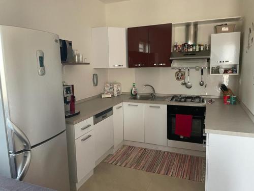 une cuisine avec des armoires blanches et un réfrigérateur dans l'établissement Villa Lara - mit separatem extra Zimmer mit Wc und Dusche, à San Vito dei Normanni