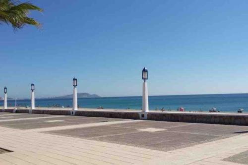 a beach with a row of light posts and the ocean at Maison Alcudia Smir, Tetouan, Mer Méditerranée in Fnidek