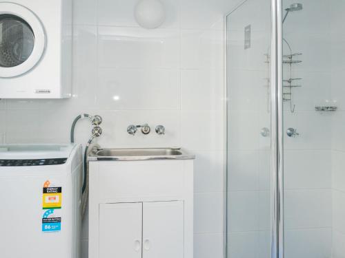 y baño blanco con lavabo y ducha. en Trickett Gardens Holiday Inn, en Gold Coast