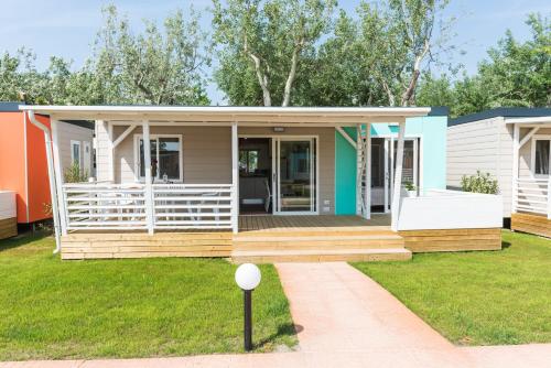 a modular home with a porch and grass at Campeggio Paradiso in Sottomarina