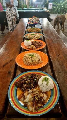 a row of plates of food on a wooden table at Tulia House Backpackers in Mombasa