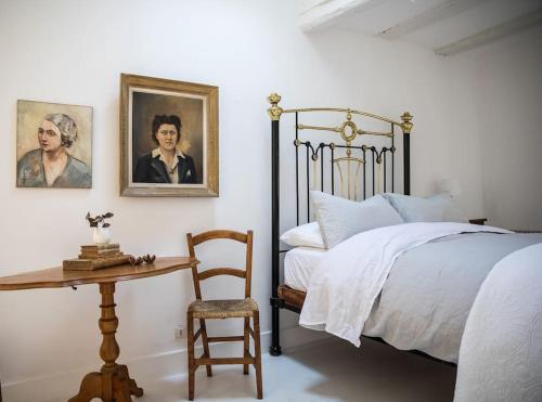 a bedroom with a bed and a table with a chair at Maison Saint Antonin in Saint-Antonin