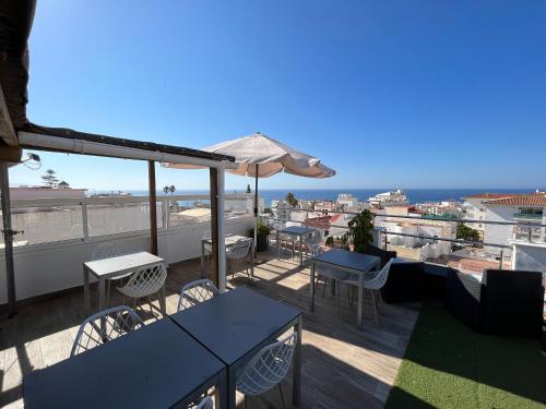 balcón con mesas, sillas y sombrilla en Hostal Don Peque Adult Recommended, en Nerja