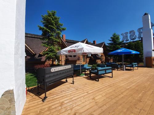 a patio with benches and umbrellas on a wooden deck at Hotel Górski in Wolbórz