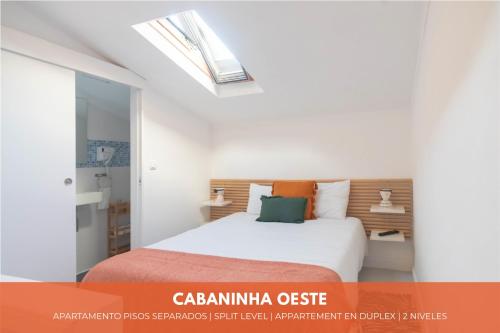 1 dormitorio con cama blanca y tragaluz en Cabanas do avô João, en Nazaré