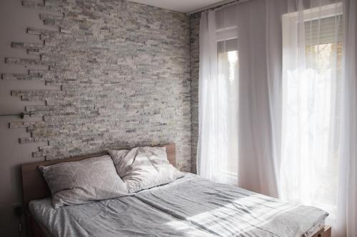 a bed in a bedroom with a brick wall at Butik Apartmanház in Fonyód