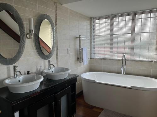 a bathroom with two sinks and a tub and mirrors at Bokamoso Views in Rustenburg