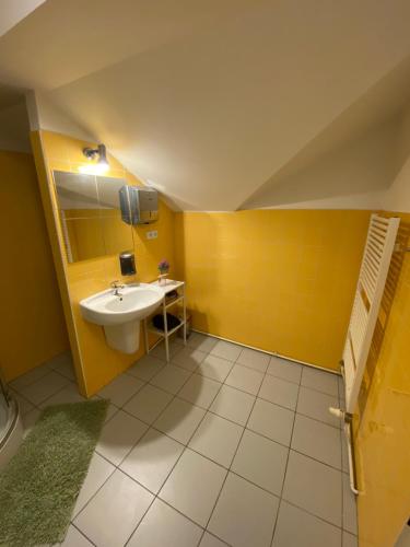 La salle de bains est pourvue d'un lavabo et d'un mur jaune. dans l'établissement Restaurace Bowling Rakovec, à Řepiště