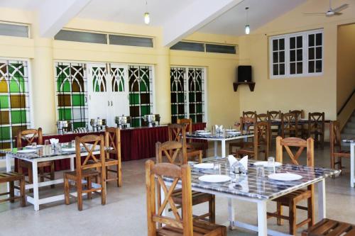 a dining room with tables and chairs and windows at Mothers Bounty by Lazo , Coorg in Madikeri