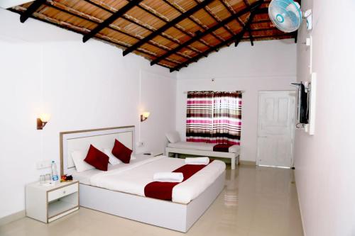 a bedroom with a white bed with red pillows at Mothers Bounty by Lazo , Coorg in Madikeri