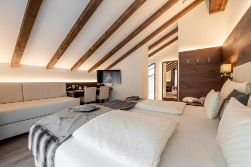 two beds in a room with a couch and a table at Arya Alpine Lodge in Selva di Val Gardena