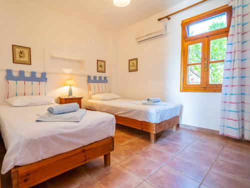 1 dormitorio con 2 camas y ventana en Zefiros House, en Frangokastello