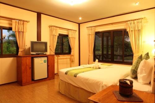 a bedroom with a bed and a tv and windows at Busai Country View in Wang Nam Khieo