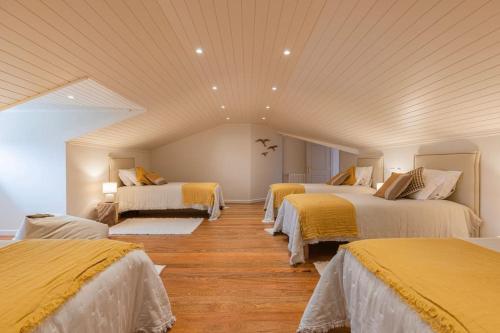 a room with four beds with yellow sheets and wood floors at Windmill Beachfront Villa in Colares
