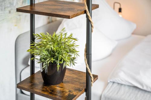 a wooden shelf with a plant on it next to a bed at Ruhiges und zentrales Apartment in Hüttenfeld in Lampertheim