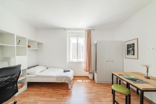1 dormitorio con cama, escritorio y mesa en Central City Suits en Wiener Neustadt