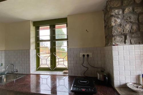a kitchen with a stove and a window in it at Thendral: Delightful homestay on a hill near Ooty in Naduvattam