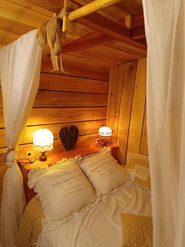 a bed with two lamps and two pillows on it at Roulotte Ô Rêves Atypiques in Boucé
