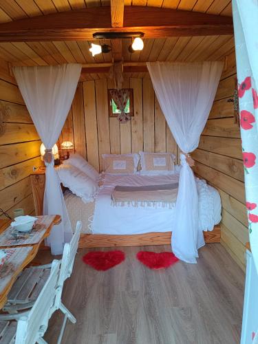 a bedroom with a bed in a log cabin at Roulotte Ô Rêves Atypiques in Boucé