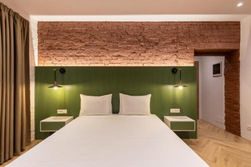 - une chambre avec un grand lit et une tête de lit verte dans l'établissement Vatër Apartments, à Tirana