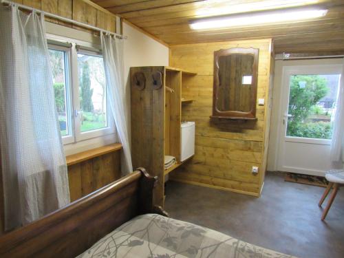 a bedroom in a log cabin with a bed and a window at LA BAROUD' ER in Voillecomte