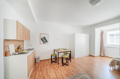 a kitchen with a sink and a table in a room at Central City Suits in Wiener Neustadt
