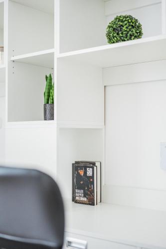a desk with a chair and a book on a shelf at Central City Suits in Wiener Neustadt