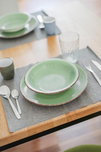 a table with green plates and silverware on a table at Central City Suits in Wiener Neustadt