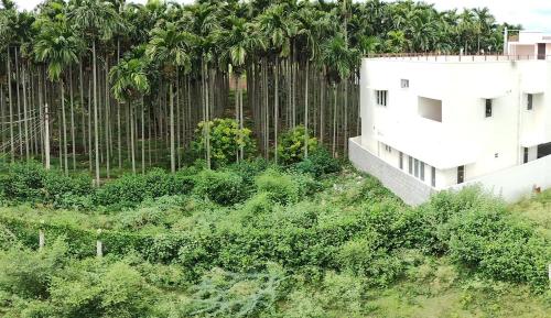 um edifício em frente a uma cerca com palmeiras em SHI's Shambhavi homestay -On the way to Isha, Maruthamalai em Coimbatore