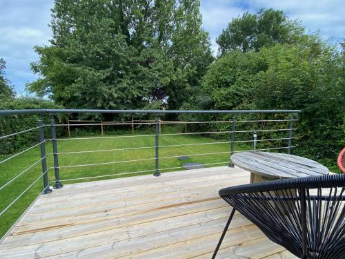 une terrasse en bois avec un banc et un champ dans l'établissement Le studio de la Noire Choque - Bain nordique, à Audembert