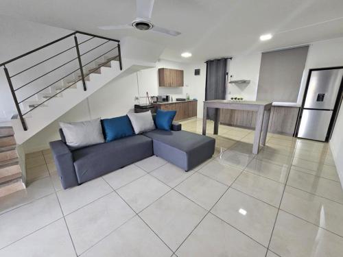 Una sala de estar con un sofá azul y una cocina. en Green Village Duplex, en Grand Gaube