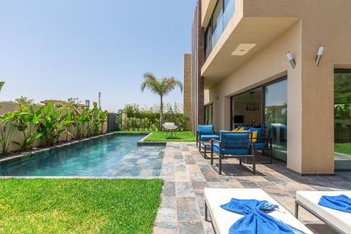 a backyard with a swimming pool and a house at Villa Nounja Golf Amelkis Marrakech in Marrakech