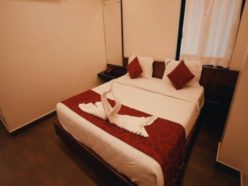 two white towels on two beds in a hotel room at Aparupa Ambience in Port Blair