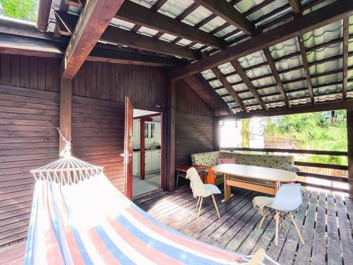 een hangmat op een terras met een tafel en stoelen bij Mazurek domek letniskowy do wynajęcia na mazurach in Kierwik