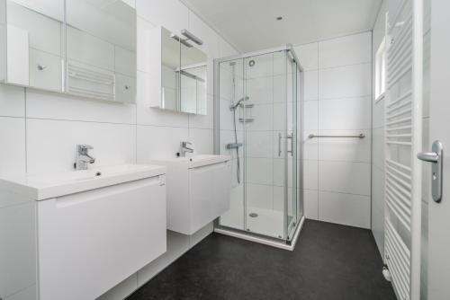 a white bathroom with two sinks and a shower at Duinpark Westerschouwen in Burgh Haamstede